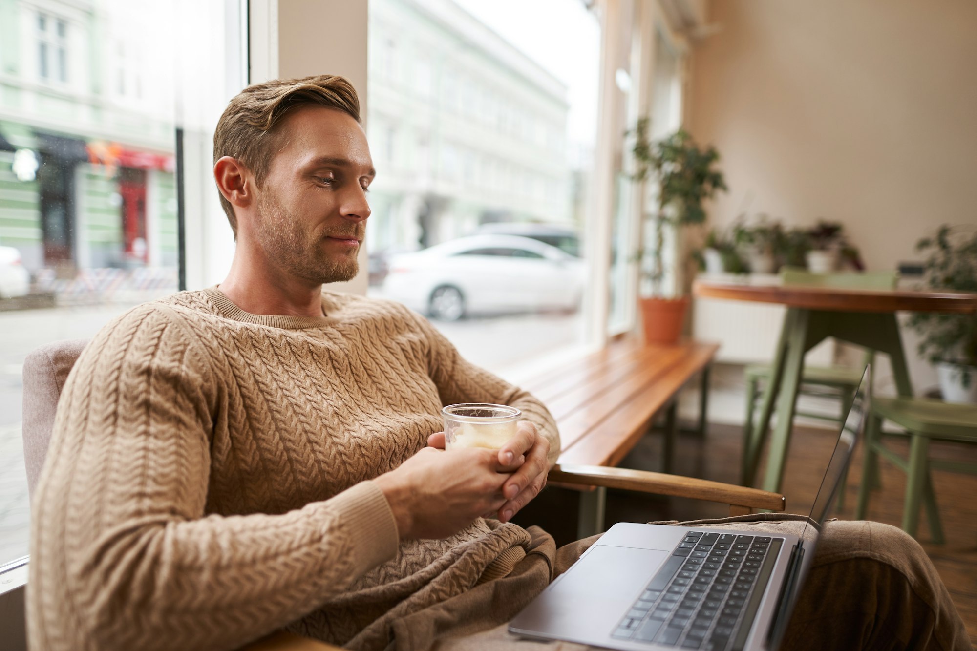 Retrato de un empresario, un nómada digital sentado en una cafetería con una taza de capuchino, mirando