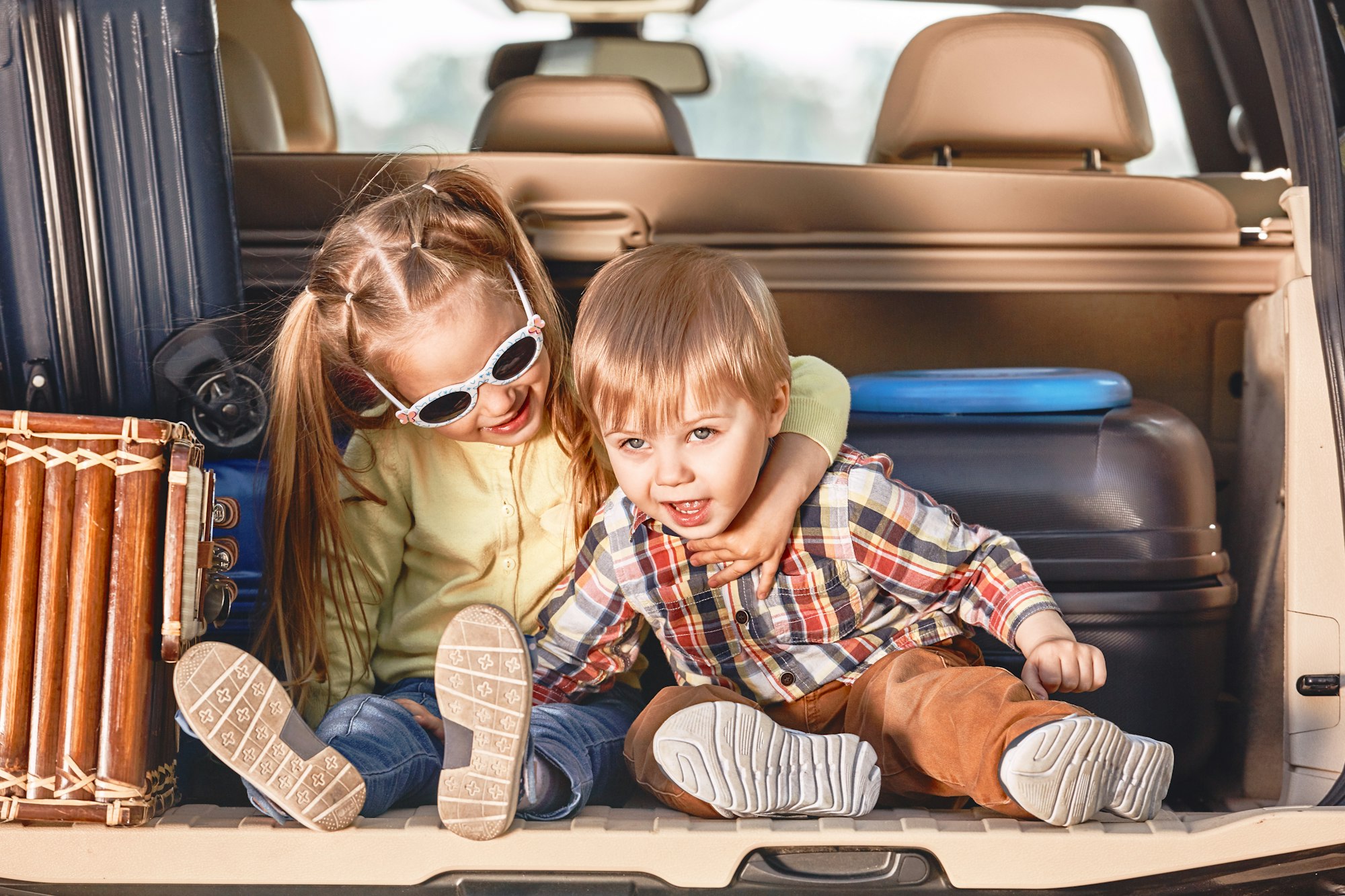 Inizio del viaggio. Bambini piccoli e carini nel bagagliaio di un'auto con le valigie. Viaggio in famiglia